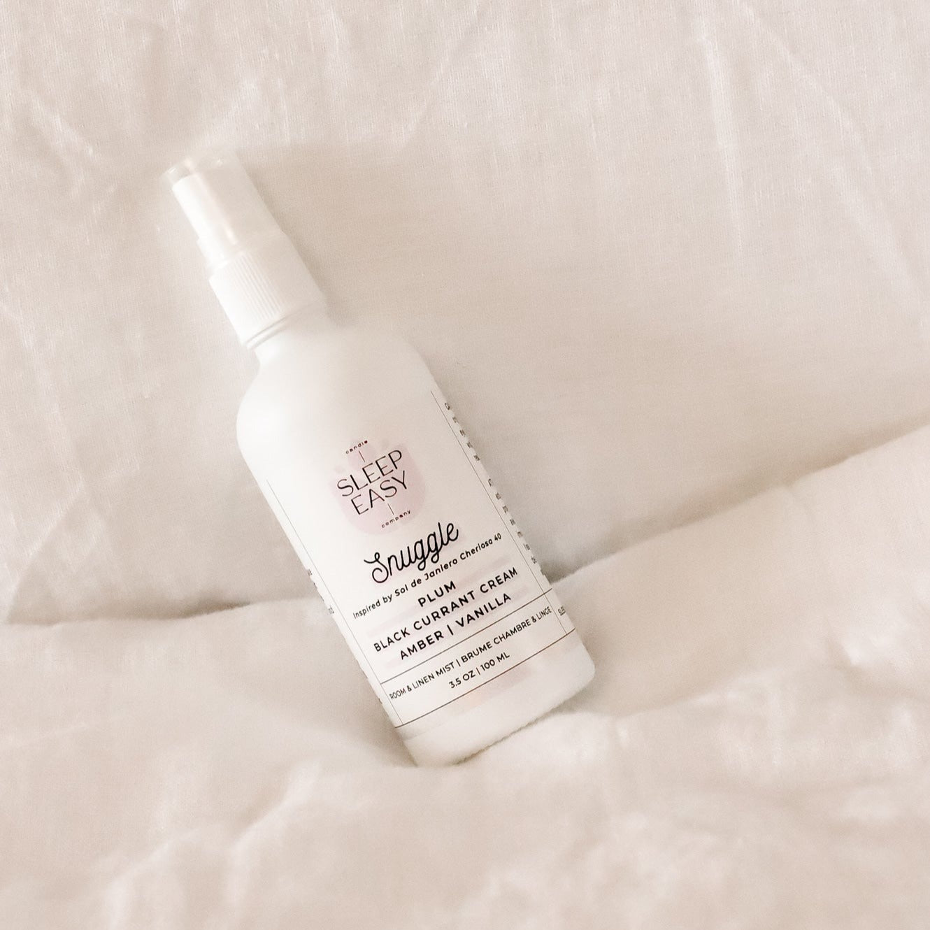Snuggle Room & Linen Mist lays on top of bedsheets.
